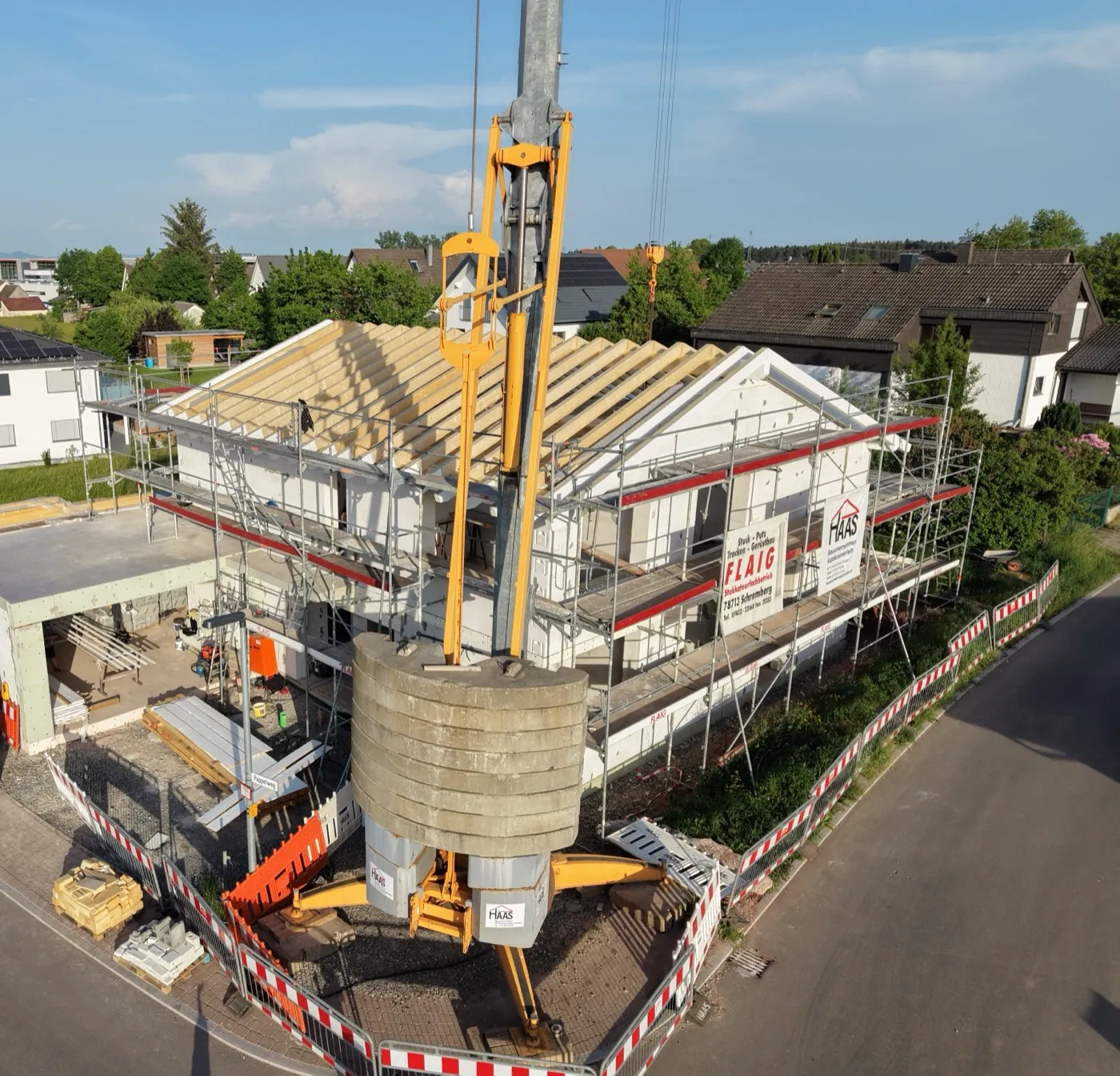 Luftaufnahme eines Rohbaus mit Dachstuhl und großem Baukran