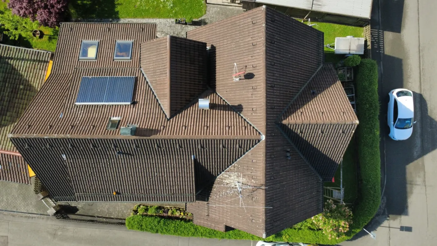 Luftaufnahme eines Einfamilienhauses mit Solaranlage, Garten und Auto in der Einfahrt