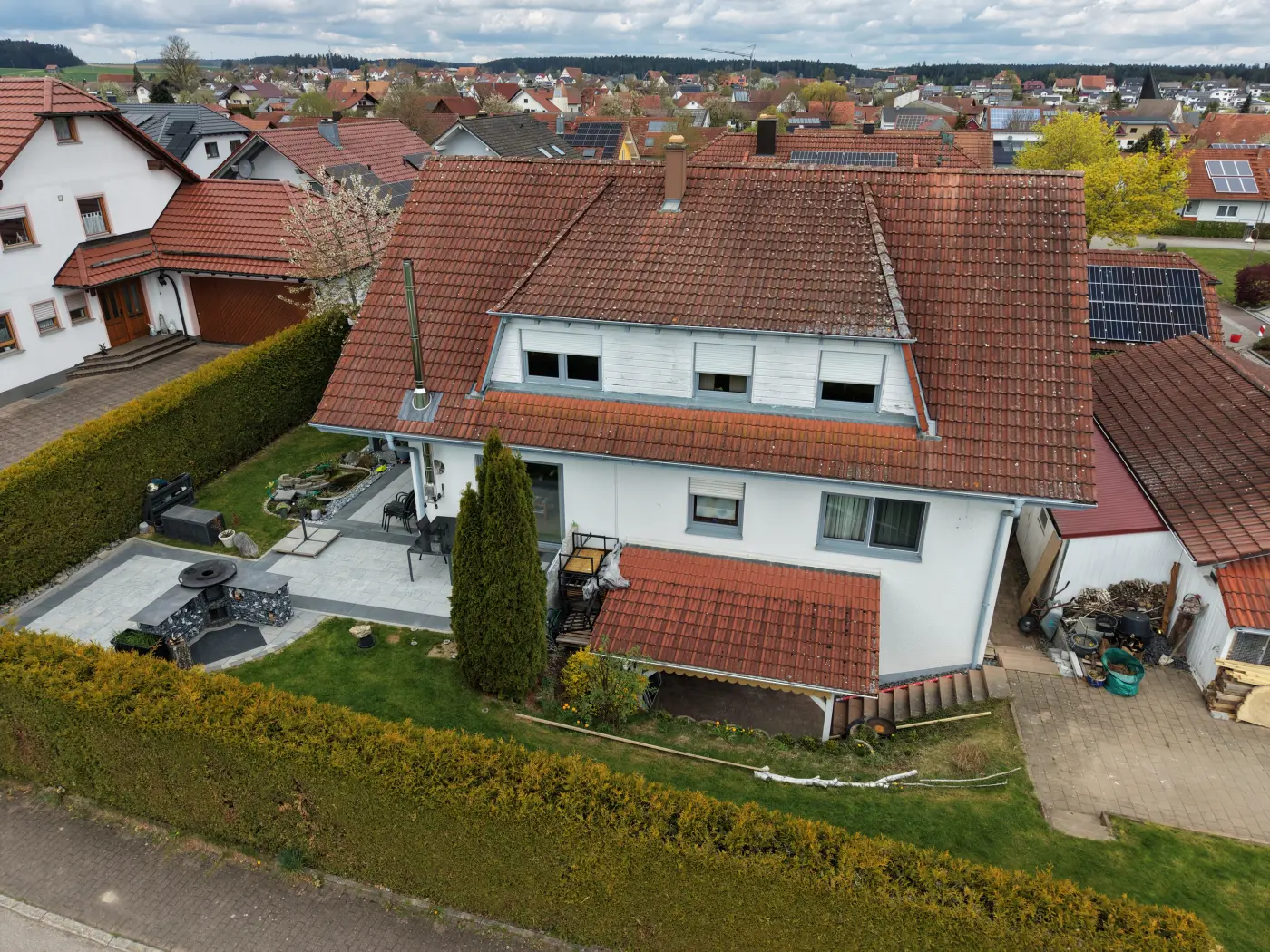 Luftaufnahme eines Einfamilienhauses mit rotem Ziegeldach und Garten von schräg oben