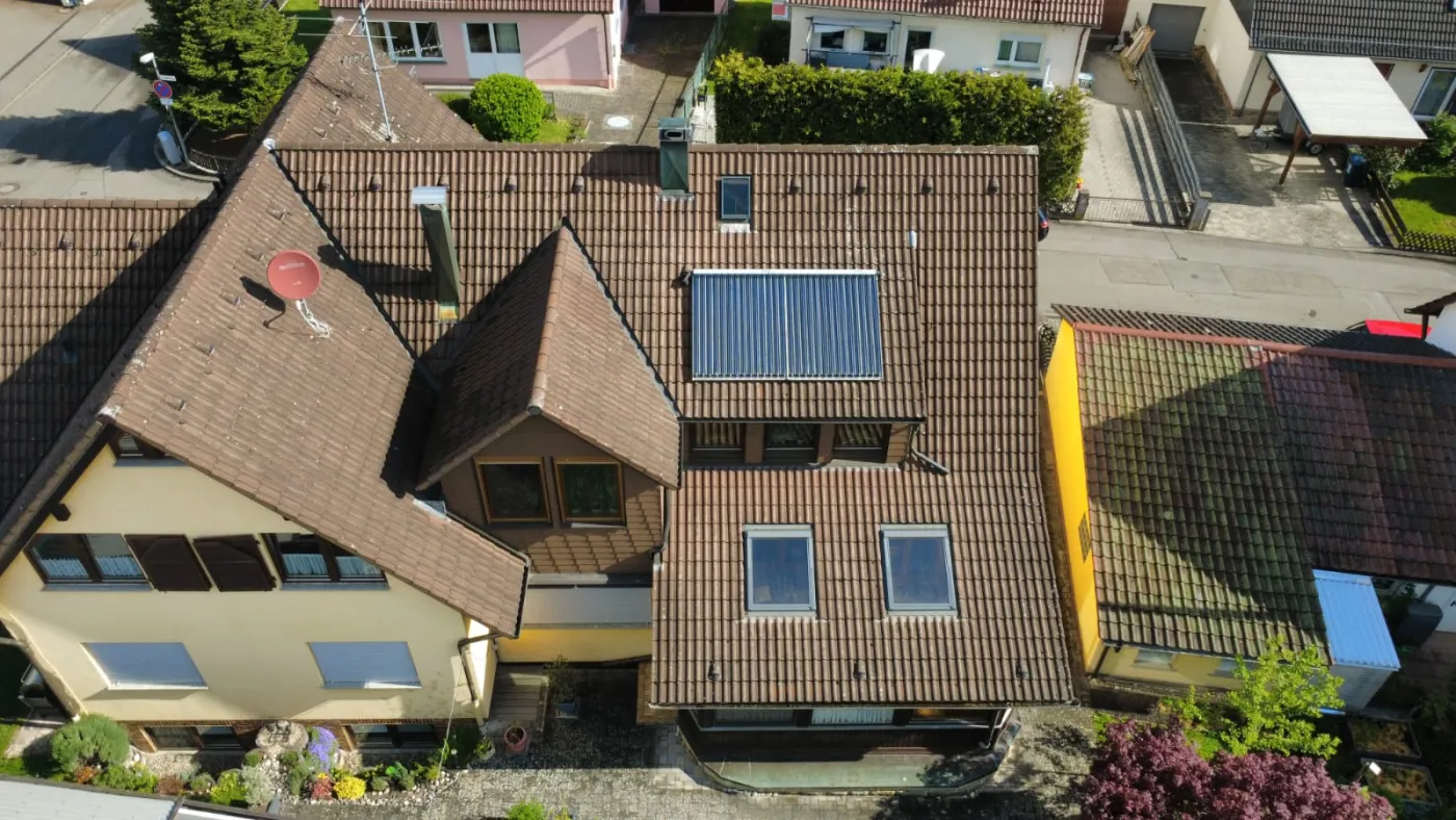 Luftaufnahme eines cremefarbenen Wohnhauses mit Solaranlage und Auto in der Einfahrt