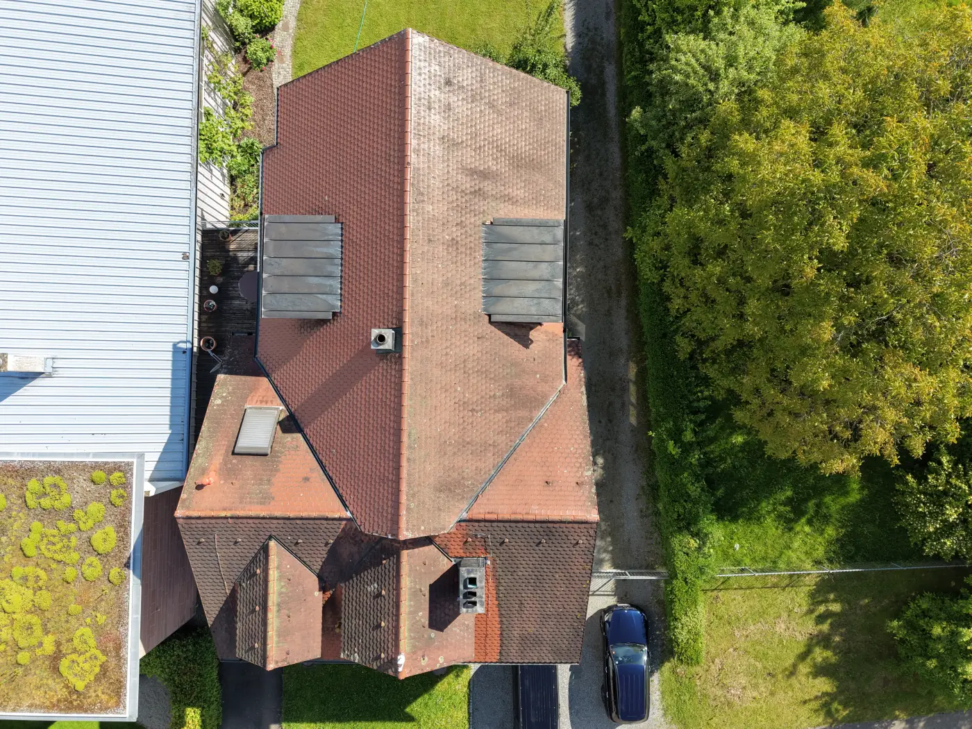 Luftaufnahme eines Hauses mit rotem Ziegeldach von oben, Einfahrt mit Fahrzeug