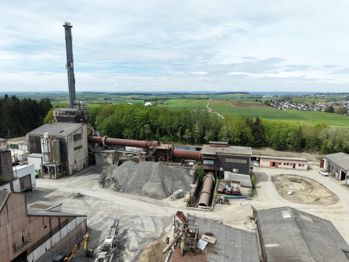 Luftaufnahme eines Industriebetriebs mit Schornstein und Werkshallen