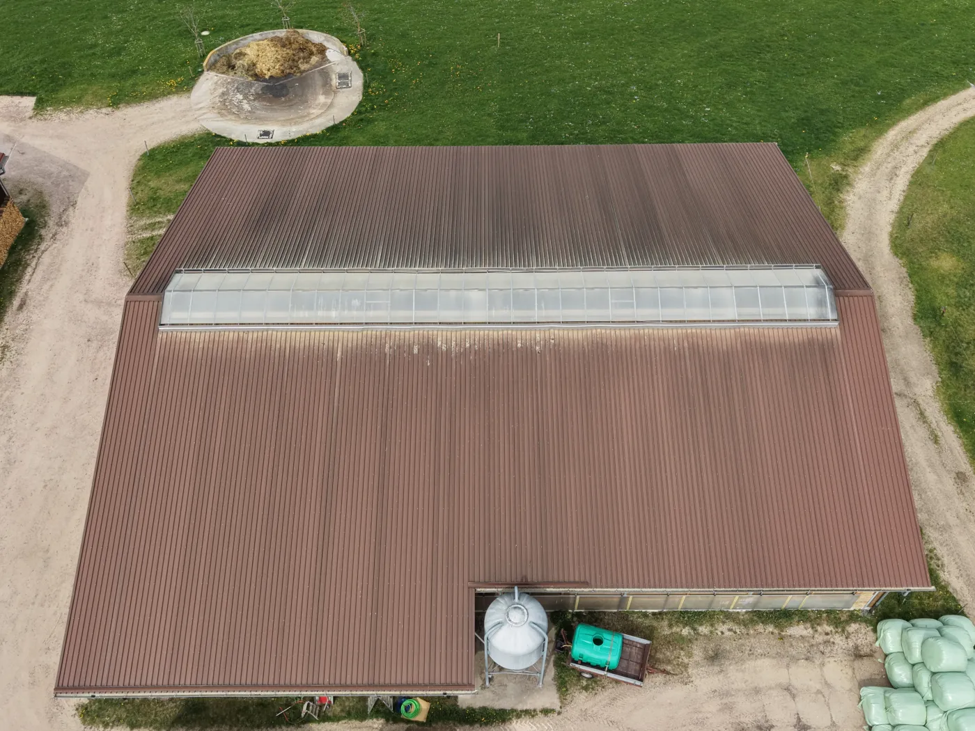 Luftaufnahme einer großen landwirtschaftlichen Halle mit Rundballen