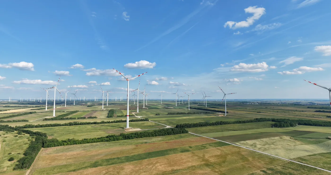 Luftaufnahme einer Freiflächen-Solaranlage neben mehreren Windkraftanlagen