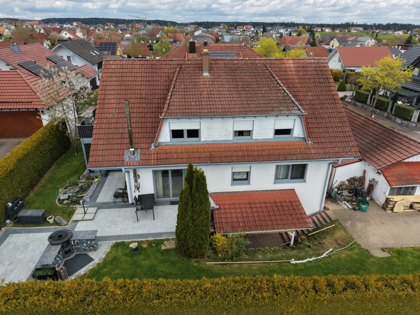 Luftaufnahme eines Einfamilienhauses mit rotem Dach und gepflegtem Grundstück